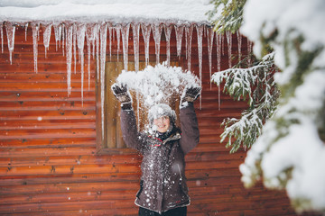 Woman having fun in front of a cottage with icicles in heavy winter.