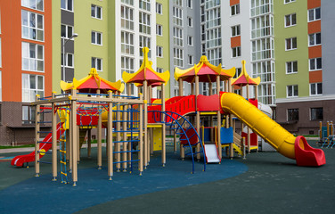 Fototapeta na wymiar Children's complex of different swings in the courtyard of a multi-storey building. Bright and safe game that can be played by children.