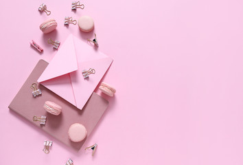 Tasty macarons with stationery on color background