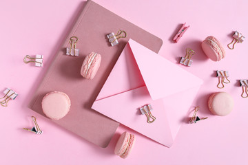 Tasty macarons with stationery on color background