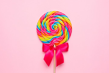 Colorful lolipop spiral with wooden stick on pink background , childhood sweets