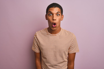 Young handsome arab man wearing striped t-shirt standing over isolated pink background afraid and shocked with surprise expression, fear and excited face.