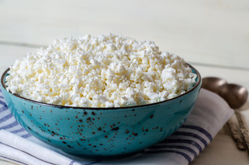 Cottage cheese, tvorog, farmer's cheese in a simple bowl, wooden background