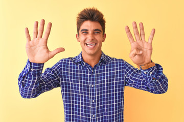 Young handsome man wearing casual shirt standing over isolated yellow background showing and pointing up with fingers number nine while smiling confident and happy.