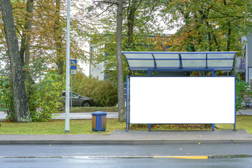 empty glass bus stop with blank white billboard near road in city mock-up