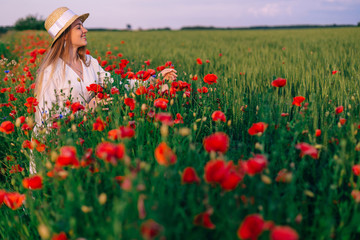 girl looks into the camera and smiles in a field with red poppie