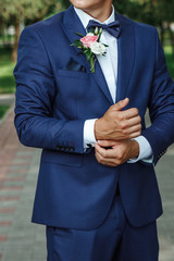 groom dressed in an elegant suit posing on a street background.