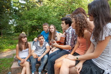 Cheerful teenagers playing guitar and singing
