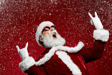 Waist up portrait of cool rock Santa roaring over red background with snow falling, copy space