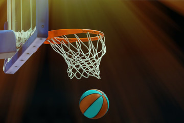 Basketball ring with a net in which the ball flies on a dark background in a sports complex. Toned