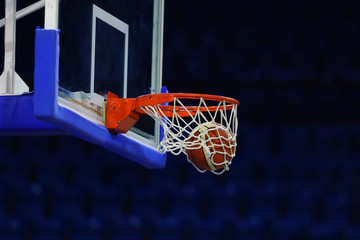 A basketball flies into the ring. On the background of a sports complex
