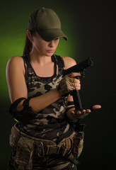 Fototapeta premium the girl in military overalls airsoft posing with a gun in his hands on a dark background in the haze