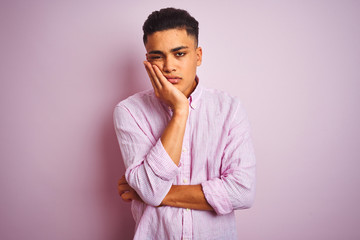 Young brazilian man wearing shirt standing over isolated pink background thinking looking tired and bored with depression problems with crossed arms.