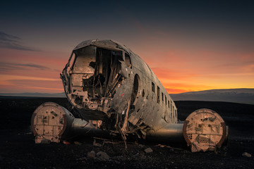 Crushed plane Dakota on black beach at the sunset