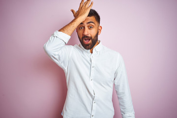 Young indian businessman wearing elegant shirt standing over isolated pink background surprised...