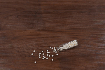 Homeopathy pills in glass bottle on wooden background
