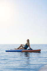 Fototapeta premium Summer holidays vacation travel. SUP Stand up paddle board. Young woman sailing on beautiful calm lagoon