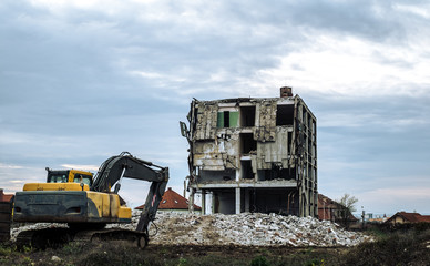 building under demolition with hydraulic excavator