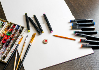 tools for children's creativity and drawing-watercolor album, watercolor paints, simple pencil, color markers, eraser on a wooden surface