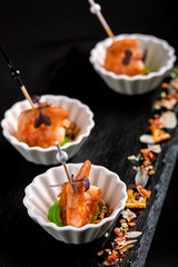 Canapes with tiger prawns on a skewer on a black background. The concept of catering food.