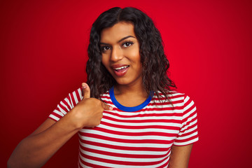 Beautiful transsexual transgender woman wearing stiped t-shirt over isolated red background with surprise face pointing finger to himself