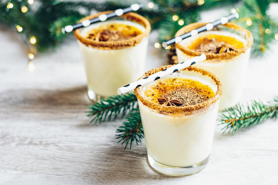 Eggnog with cinnamon and nutmeg for Christmas and winter holidays. Homemade eggnog in glasses on wooden table surface, shallow depth of the field, copy space
