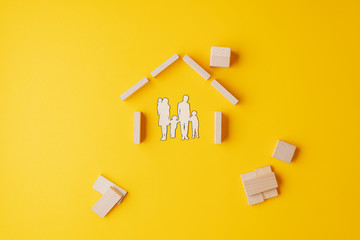 Fototapeta na wymiar Paper cut silhouette of a family in house made of wooden blocks