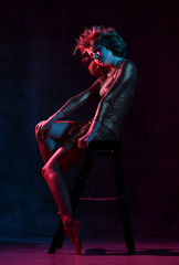 Attractive young girl in a tight shiny dress in the studio with color filters.