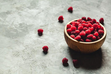 raspberries in wood bowl on gray table, vintage