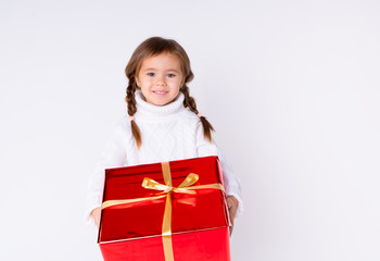 little cute girl in knitted white sweater holding a present in studio. Concept Christmas, New Year, Birthday