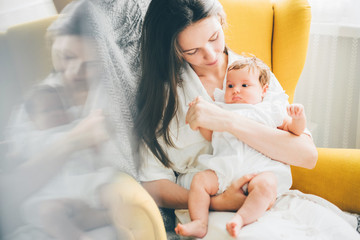 Young mother holding her newborn child. Mom nursing baby. Woman and new born girl relax in a...