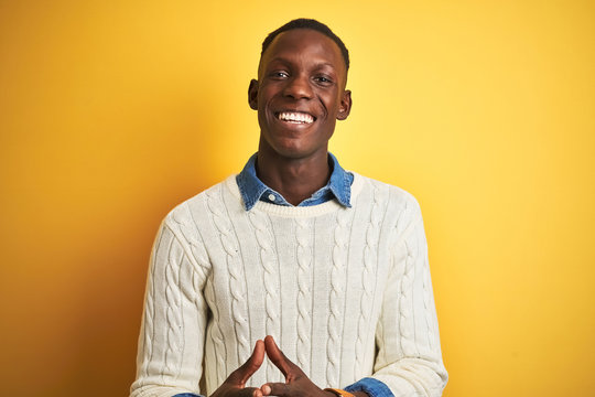 African american man wearing denim shirt and white sweater over isolated yellow background Hands together and fingers crossed smiling relaxed and cheerful. Success and optimistic