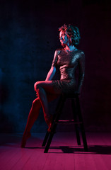 Attractive young girl in a tight shiny dress in the studio with color filters.