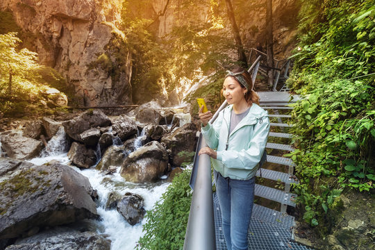 Happy asian tourist girl walk along a hinged iron trail along sheer cliffs in the canyon of the Pollat river in the Bavarian Alps