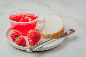 Strawberry jam. Making sandwiches with strawberry jam. Bread and strawberry jam on a white table with jar of jam and fresh strawberry.