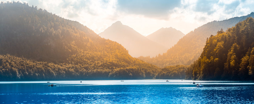 Panoramic view of lake Alpsee with tourists boating and relaxing. Tourism in Hohenschwangau village and Neuschwanstein castle