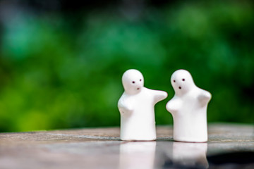 White ceramic doll Against the natural green background and bokeh