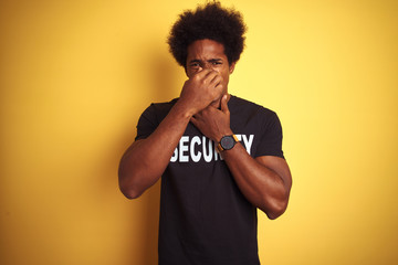 American safeguard man with afro hair wearing security uniform over isolated yellow background...