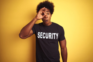 American safeguard man with afro hair wearing security uniform over isolated yellow background...