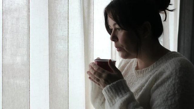 Mujer tomando café frente a ventana