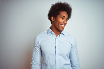 Obraz premium Young african american man with afro hair wearing elegant shirt over isolated white background looking away to side with smile on face, natural expression. Laughing confident.
