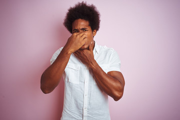 Young american man with afro hair wearing white shirt standing over isolated pink background...