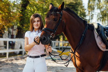 Girl taking care of her horse before horse riding and combining him. Equestrian sport at fresh air.