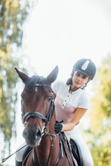 Fototapeta premium Beautiful girl jockey rides a horse in nature outdoors.