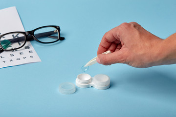 Flat composition with contact lenses, table for eye examination. Accessories for ophthalmologists. Glasses and lenses for vision correction on a blue background