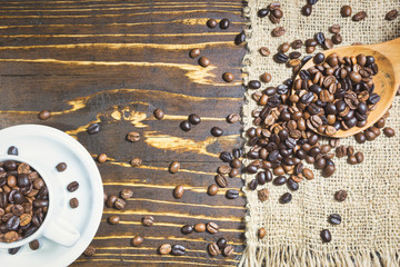 Cup with coffee beans on rustic background