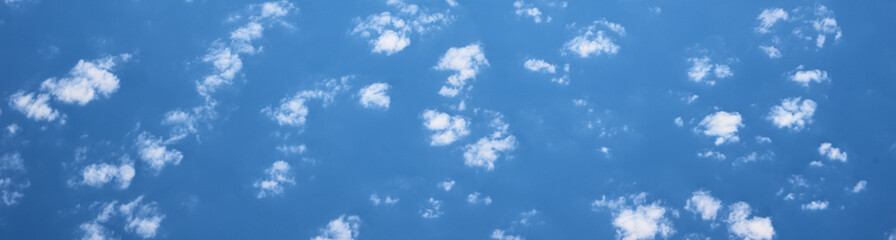 Blue cloudy sky, view from the airplane window. Aerial view of cloudscape, abstract background. Long banner