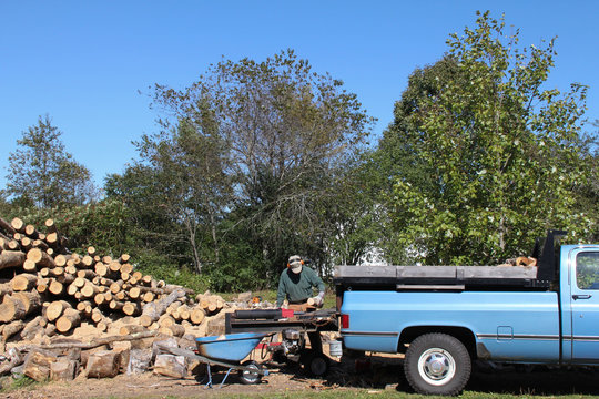 Man cutting splitting firewood with splitter and rusty old pickup truck
