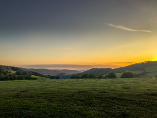 Fototapeta premium Multi colored sky of hill Velka Lhota Beskydy area sky and clouds play with many colors with view to surround the nature area around many small hills and mountains around capturing during sunset.