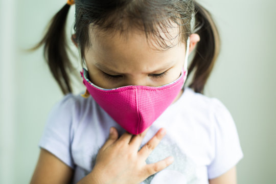 A sick child coughing from air pollution, wearing a mask. Lung disease.